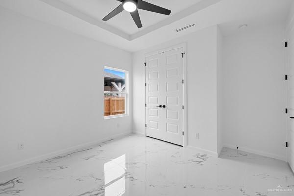 unfurnished room with ceiling fan and a raised ceiling