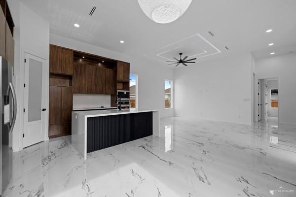 kitchen featuring sink, dark brown cabinets, a center island, and stainless steel refrigerator with ice dispenser