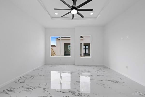 spare room with ceiling fan and a tray ceiling