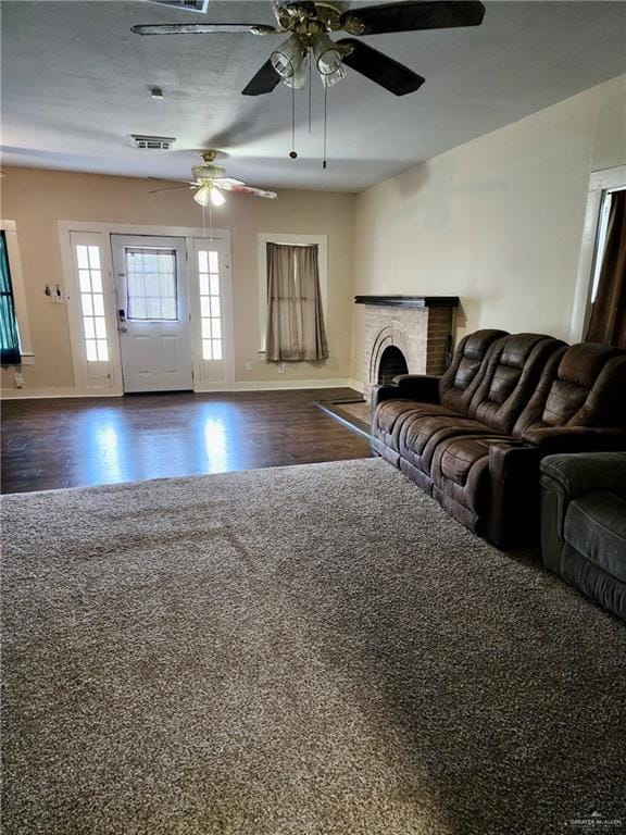 222 W Buchanan St, Harlingen, TX 78550 - living area featuring visible vents, a brick fireplace, baseboards, ceiling fan, and dark wood finished floors