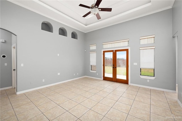 tiled empty room featuring a raised ceiling, ornamental molding, ceiling fan, and french doors