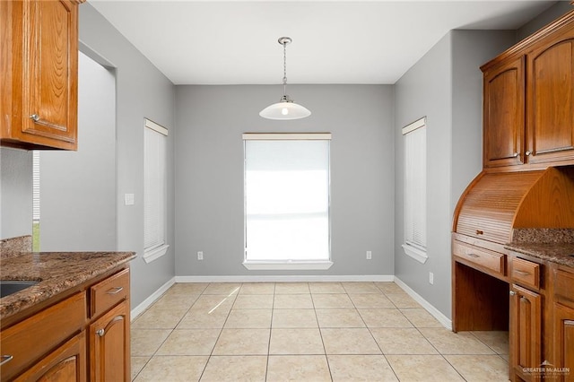 kitchen featuring stone counters, pendant lighting, and light tile patterned floors