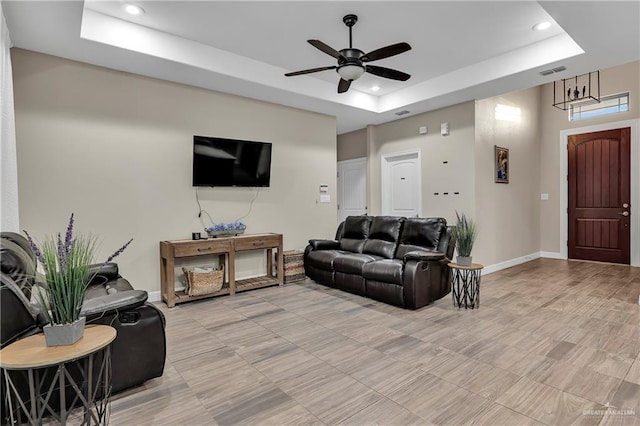 living room featuring a raised ceiling and ceiling fan