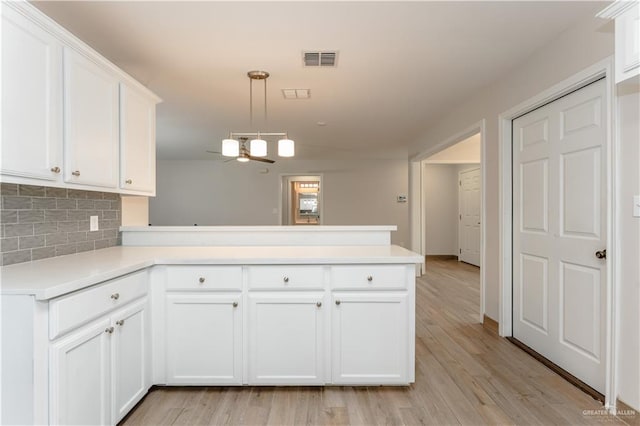 kitchen with pendant lighting, white cabinets, ceiling fan, light wood-type flooring, and kitchen peninsula