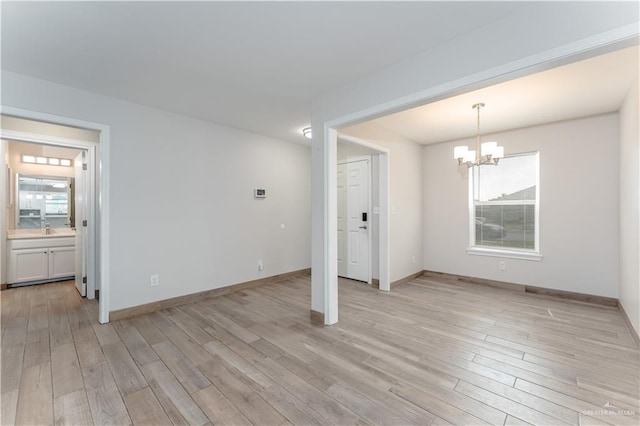 empty room with light hardwood / wood-style floors and an inviting chandelier