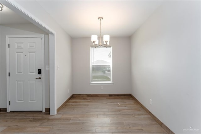 unfurnished dining area with a chandelier and light hardwood / wood-style floors