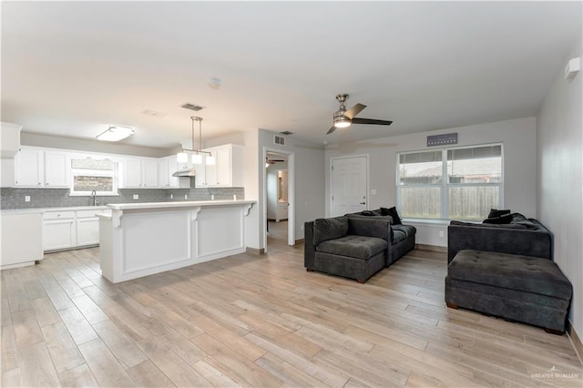 living room featuring ceiling fan, sink, and light wood-type flooring