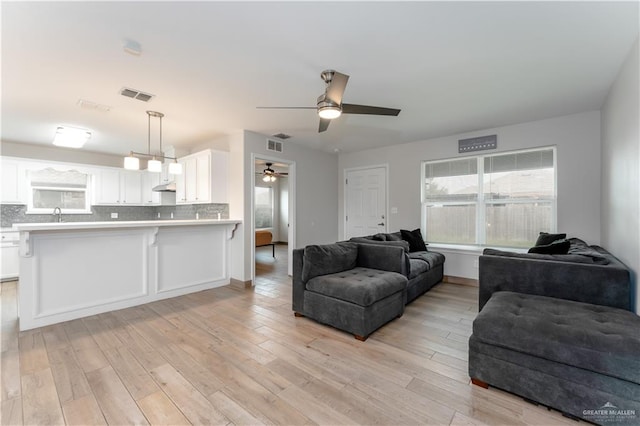 living room with ceiling fan, light hardwood / wood-style floors, and sink