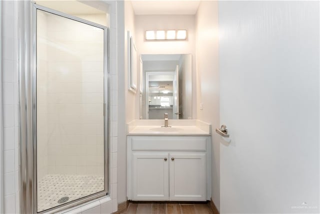 bathroom with wood-type flooring, vanity, and a shower with door