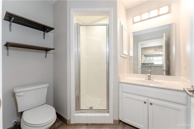 bathroom featuring vanity, hardwood / wood-style flooring, toilet, and a shower with shower door