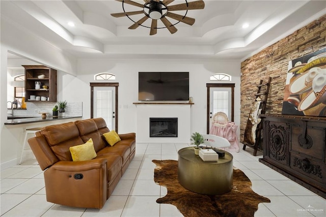 living room with a raised ceiling, ceiling fan, sink, and light tile patterned flooring