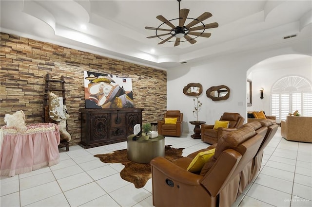 living room featuring light tile patterned floors, a raised ceiling, and ceiling fan