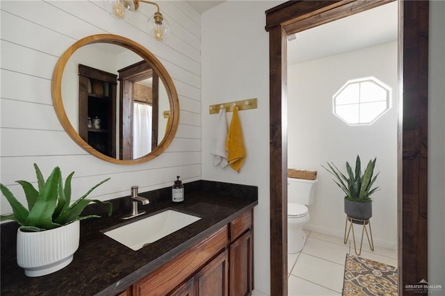 bathroom featuring tile patterned floors, vanity, toilet, and wooden walls