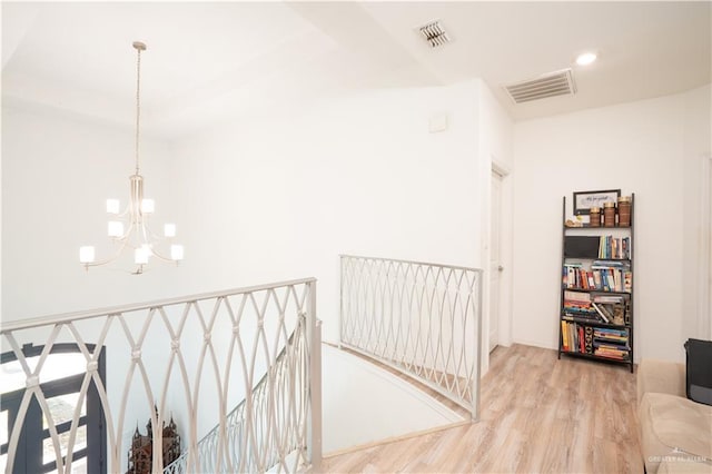 corridor with hardwood / wood-style flooring and a chandelier