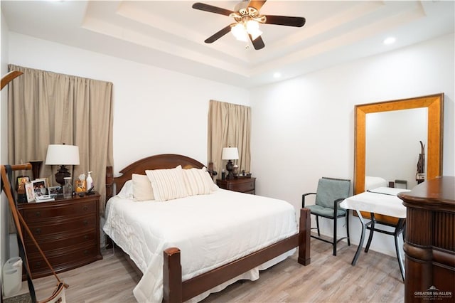 bedroom featuring a tray ceiling, light hardwood / wood-style flooring, and ceiling fan