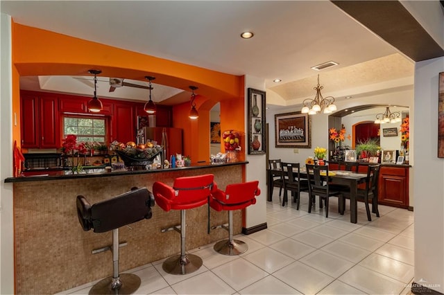 bar featuring stainless steel fridge, light tile patterned flooring, pendant lighting, and a notable chandelier