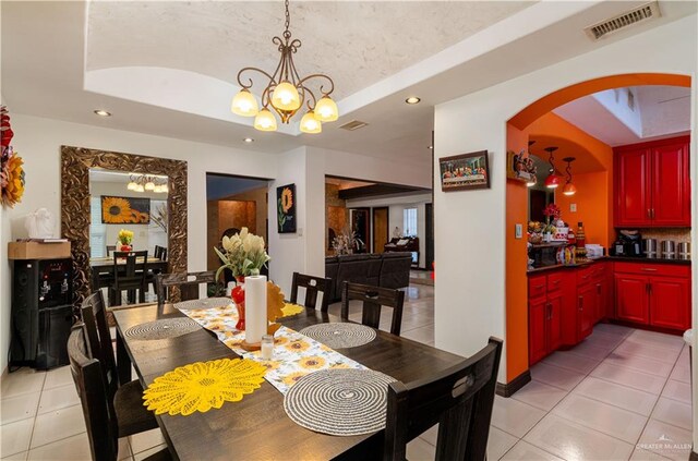 tiled dining room with a raised ceiling and an inviting chandelier