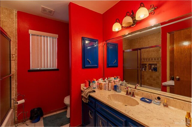 full bathroom featuring tile patterned floors, vanity, toilet, and bath / shower combo with glass door