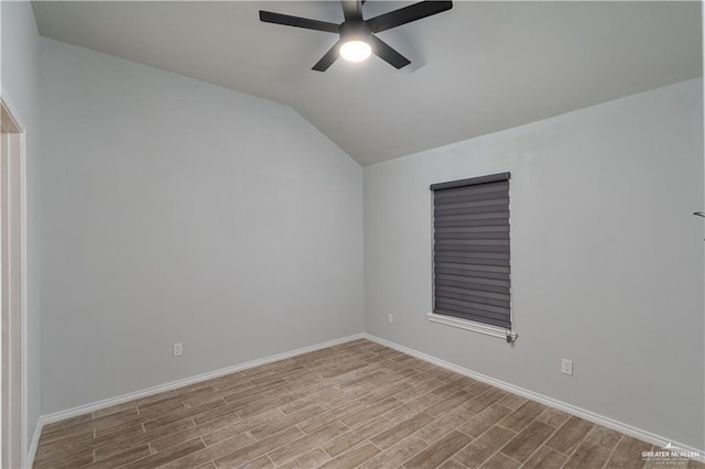 spare room with ceiling fan, vaulted ceiling, and light wood-type flooring