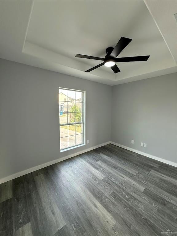 empty room with dark wood-type flooring, baseboards, and ceiling fan