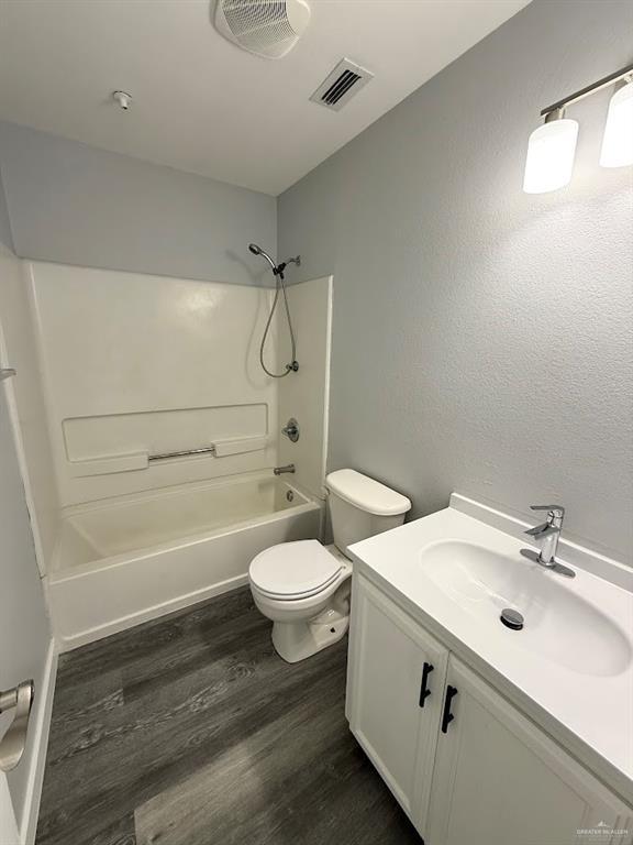 full bathroom featuring wood finished floors, shower / bathing tub combination, vanity, toilet, and visible vents