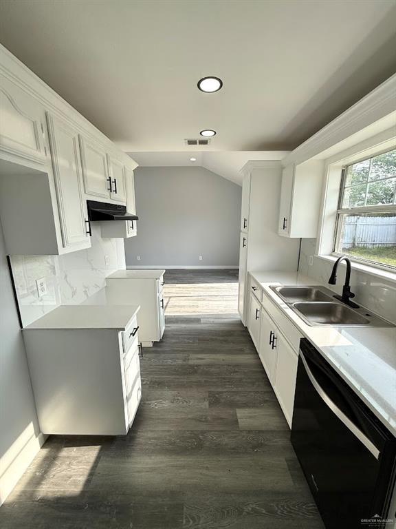 kitchen with dark wood-style floors, under cabinet range hood, light countertops, dishwasher, and a sink