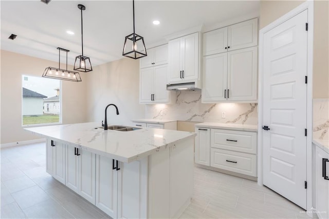 kitchen with white cabinetry, sink, hanging light fixtures, and a center island with sink