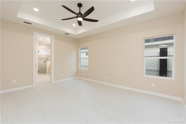 spare room featuring a tray ceiling and ceiling fan