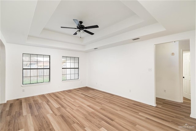 unfurnished room featuring a ceiling fan, a raised ceiling, visible vents, and light wood-style flooring