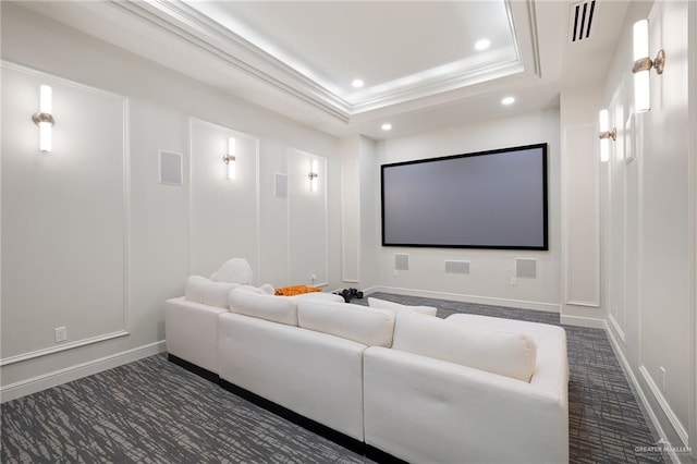 carpeted home theater room with a raised ceiling and ornamental molding