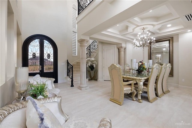 dining area with french doors, a towering ceiling, decorative columns, coffered ceiling, and a notable chandelier