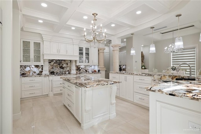 kitchen with a center island, white cabinetry, ornate columns, and backsplash