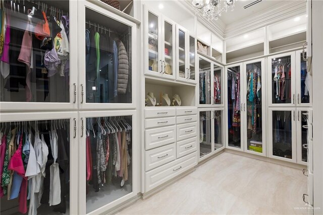 spacious closet with an inviting chandelier