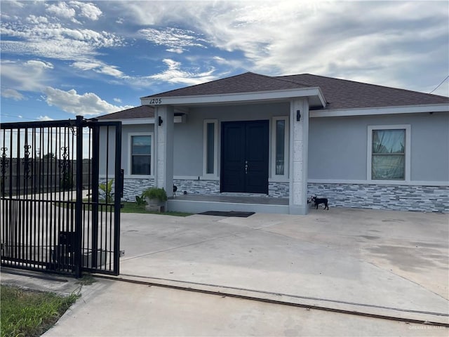 2205 Griffin Pass, Edinburg, TX 78542 - view of front facade featuring stone siding, a gate, a shingled roof, and stucco siding