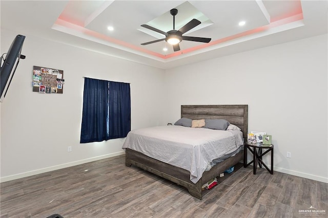 bedroom featuring a tray ceiling, recessed lighting, wood finished floors, and baseboards