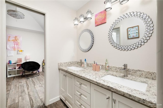 bathroom featuring double vanity, baseboards, a sink, and wood finished floors