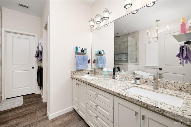 bathroom featuring visible vents, a sink, a shower stall, and wood finished floors