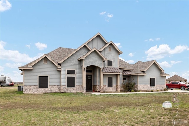 craftsman-style house featuring board and batten siding, a standing seam roof, metal roof, stone siding, and a front lawn