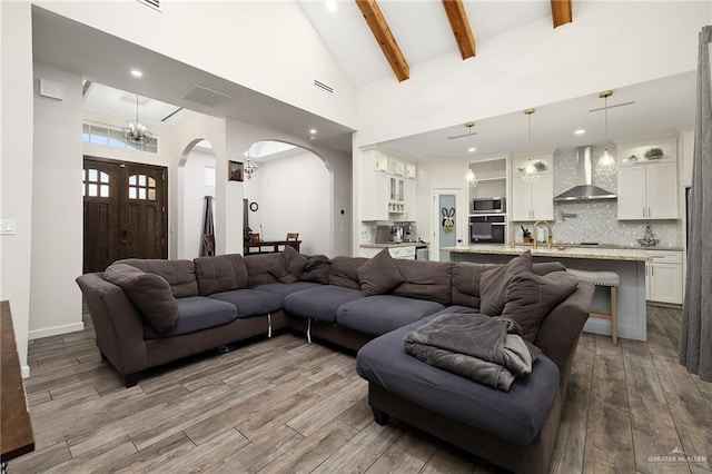 living room with visible vents, arched walkways, beamed ceiling, wood finished floors, and high vaulted ceiling