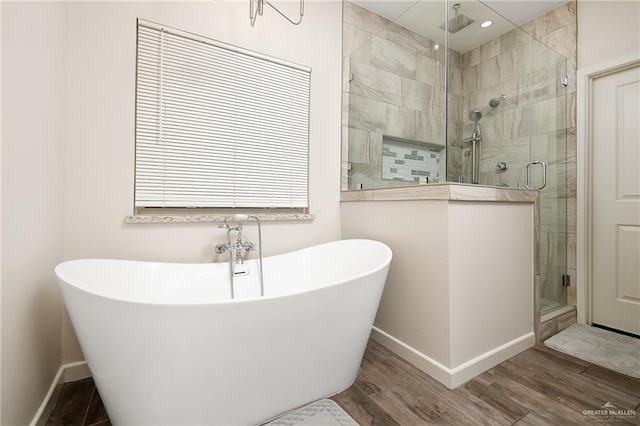 bathroom featuring a freestanding tub, baseboards, wood finished floors, and a stall shower