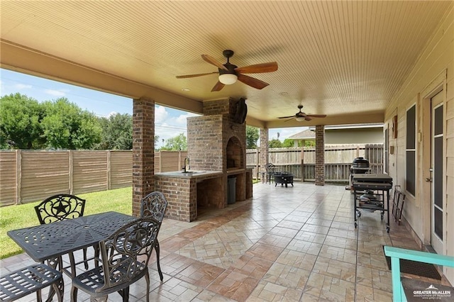 view of patio / terrace featuring ceiling fan, sink, and an outdoor fireplace