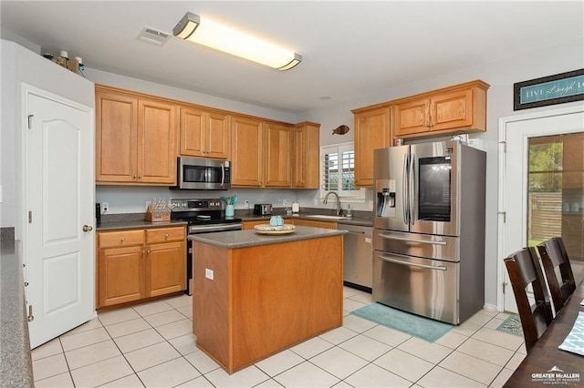 kitchen with a center island, sink, light tile patterned floors, and stainless steel appliances