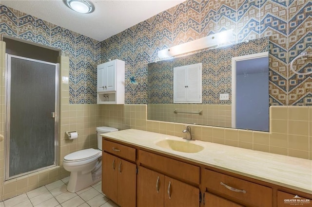 bathroom with vanity, tile walls, tile patterned flooring, toilet, and a shower with shower door