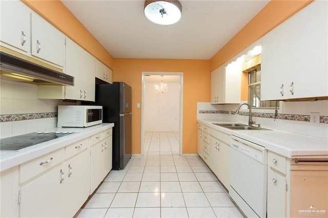 kitchen featuring white appliances, backsplash, sink, light tile patterned floors, and white cabinetry