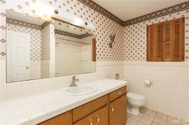 bathroom featuring tile patterned flooring, vanity, tile walls, and toilet