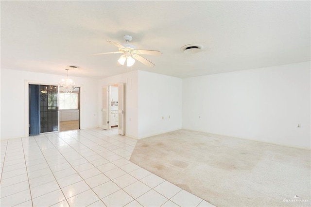 tiled spare room with ceiling fan with notable chandelier