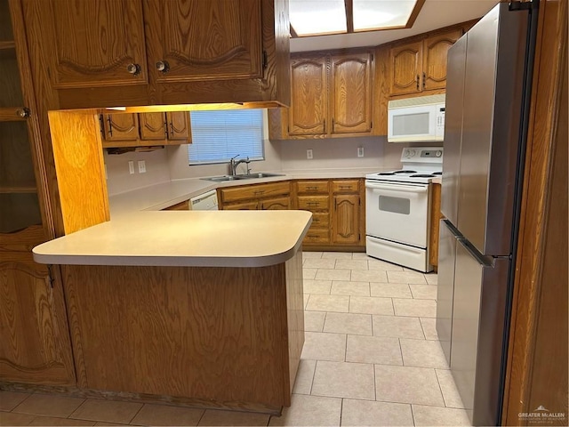 2711 Ashley Ct, Pharr, TX 78577 - kitchen with a peninsula, white appliances, a sink, light countertops, and brown cabinets