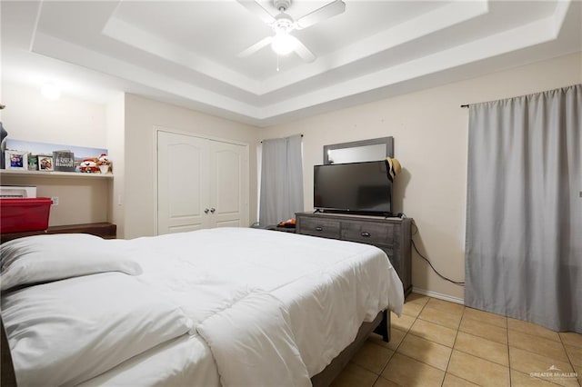 bedroom featuring light tile patterned floors, a tray ceiling, and a ceiling fan