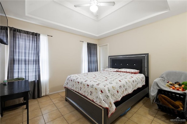 bedroom featuring tile patterned flooring, a tray ceiling, and ceiling fan