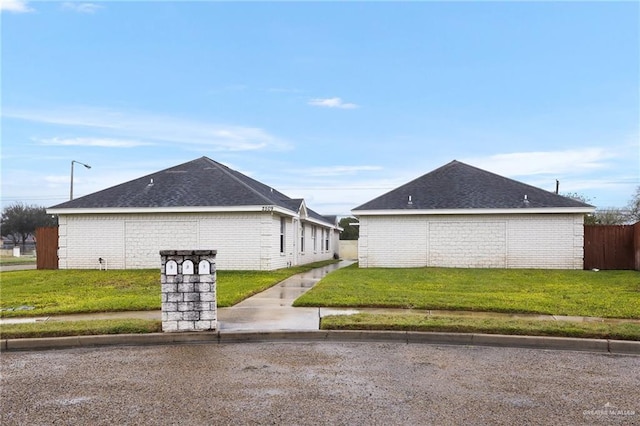 view of property exterior with fence, a lawn, and brick siding